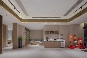 A modern hotel lobby with a reception desk, seating area, and a large potted plant.