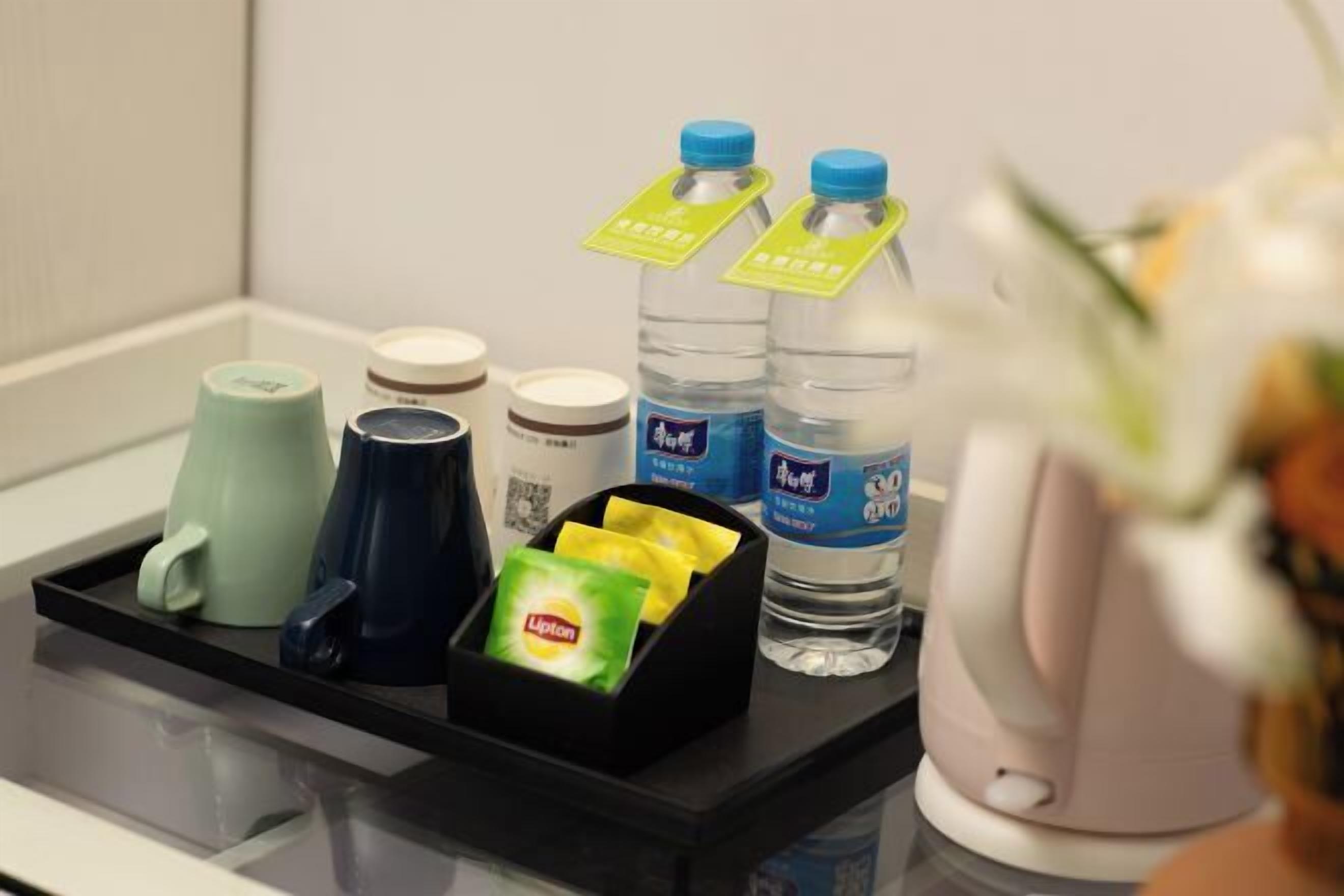 A tray with a mug, a cup, a bottle, and a box containing a Lipton tea packet.