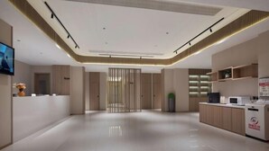 Un vestíbul d'hotel modern amb una recepció, una zona d'espera i una cuineta.