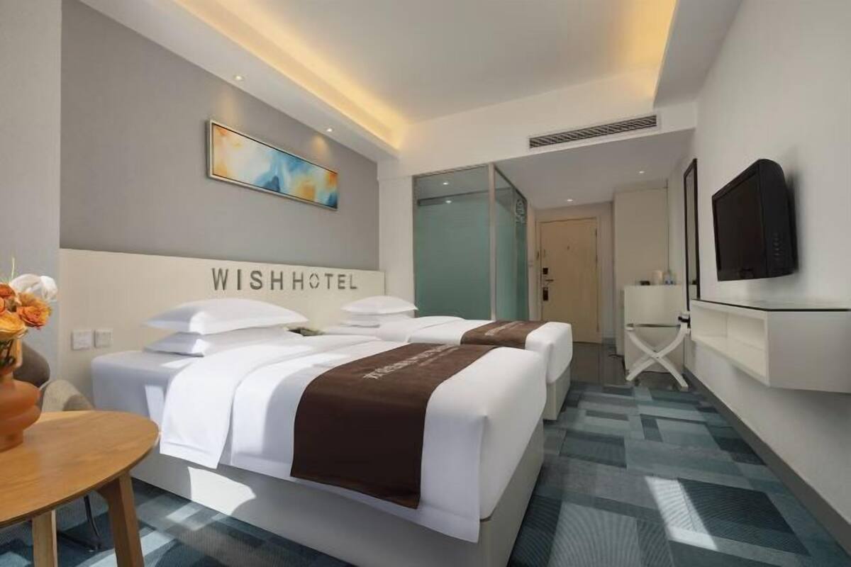 Une chambre d’hôtel moderne équipée de deux lits, d’un bureau et d’une télévision.