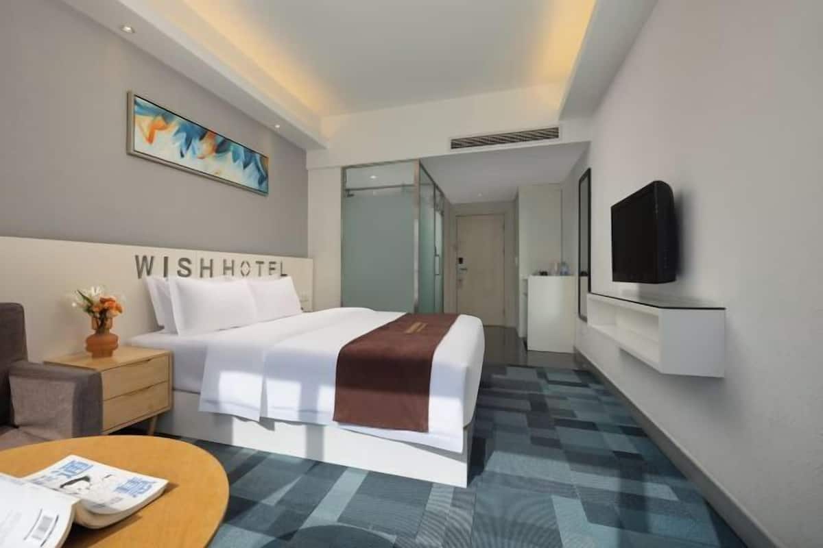 Une chambre d’hôtel avec un lit, une télévision, un bureau et un tableau au mur.