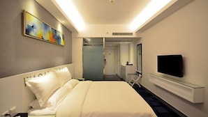 Habitació d'hotel amb un llit, un televisor penjat a la paret i un quadre a la pared.