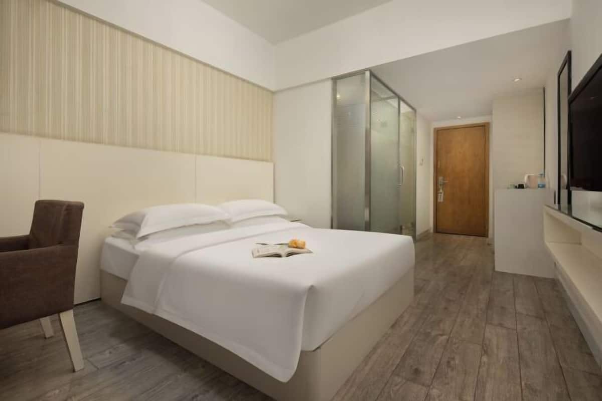Une chambre d’hôtel moderne équipée d’un lit, d’une chaise, d’un téléviseur et d’une porte coulissante.