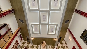 Un hall amplio con piso a cuadros, una fuente decorativa en el centro y un diseño de techo moderno con iluminación empotrada.