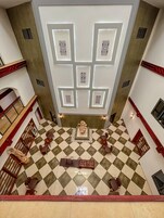 Un hall amplio con piso a cuadros, una fuente decorativa en el centro y un diseño de techo moderno con iluminación empotrada.
