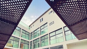 Un edificio moderno con piscina, ventanas amplias y una estructura de techo geométrica.