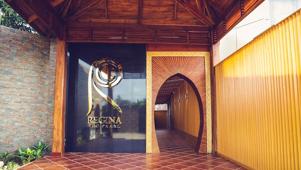 Una entrada de edificio moderna con un muro de piedra, un arco de madera y un suelo de baldosas.