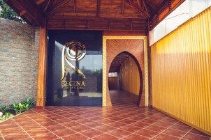 Una entrada de edificio moderna con un muro de piedra, un arco de madera y un suelo de baldosas.