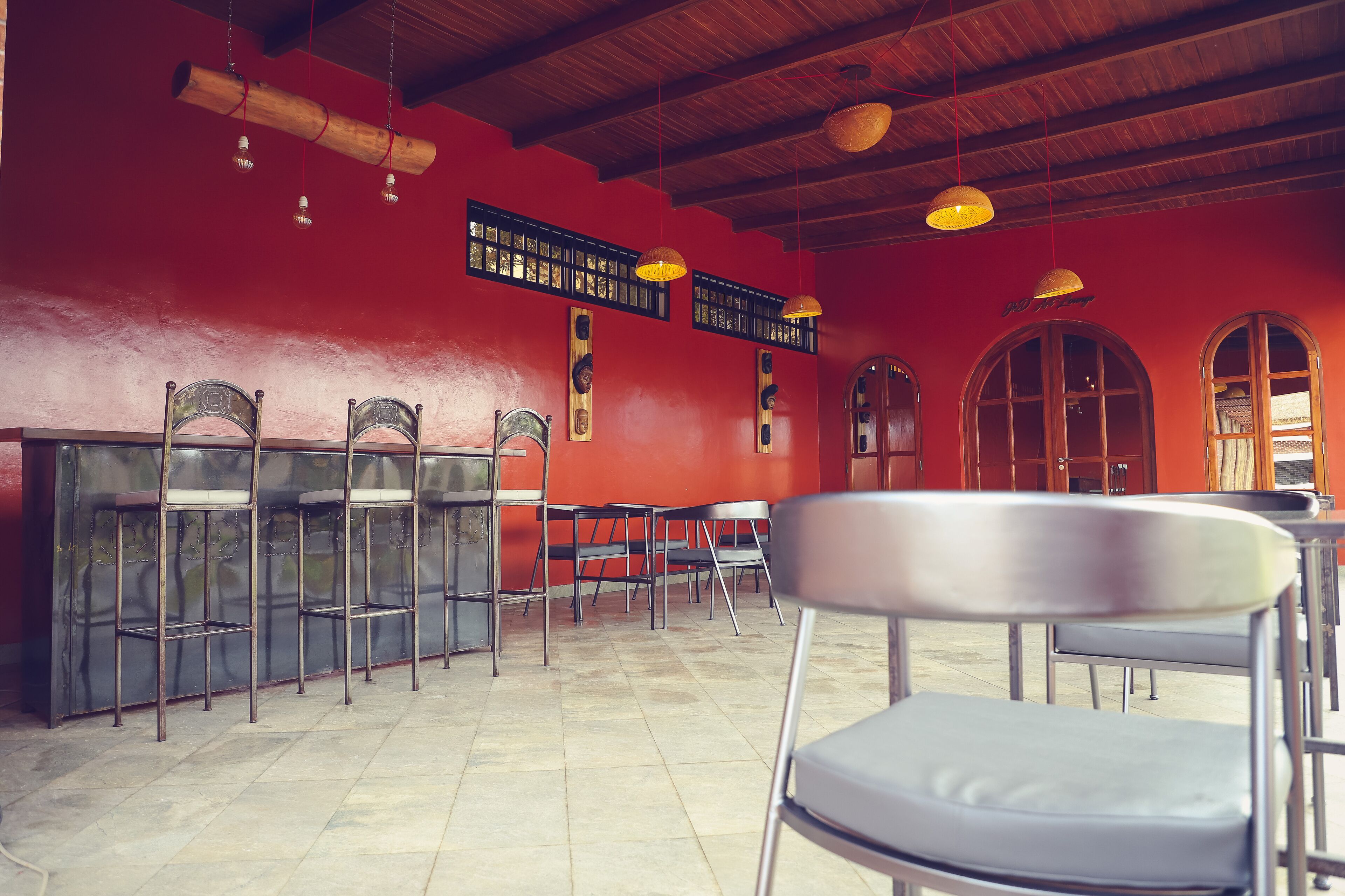 A restaurant with red walls, wooden ceiling, and metal chairs.