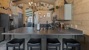 A spacious kitchen with a large island, stainless steel appliances, and a modern chandelier. - Magical Manor – Castle-Themed Pool Home w/ Hot Tub, Minutes to Disney (Davenport)
