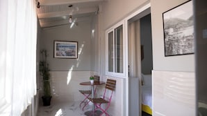A small balcony with a table, chairs, a potted plant, and a bed in the background. - Hotel Jonian (Sarandë)