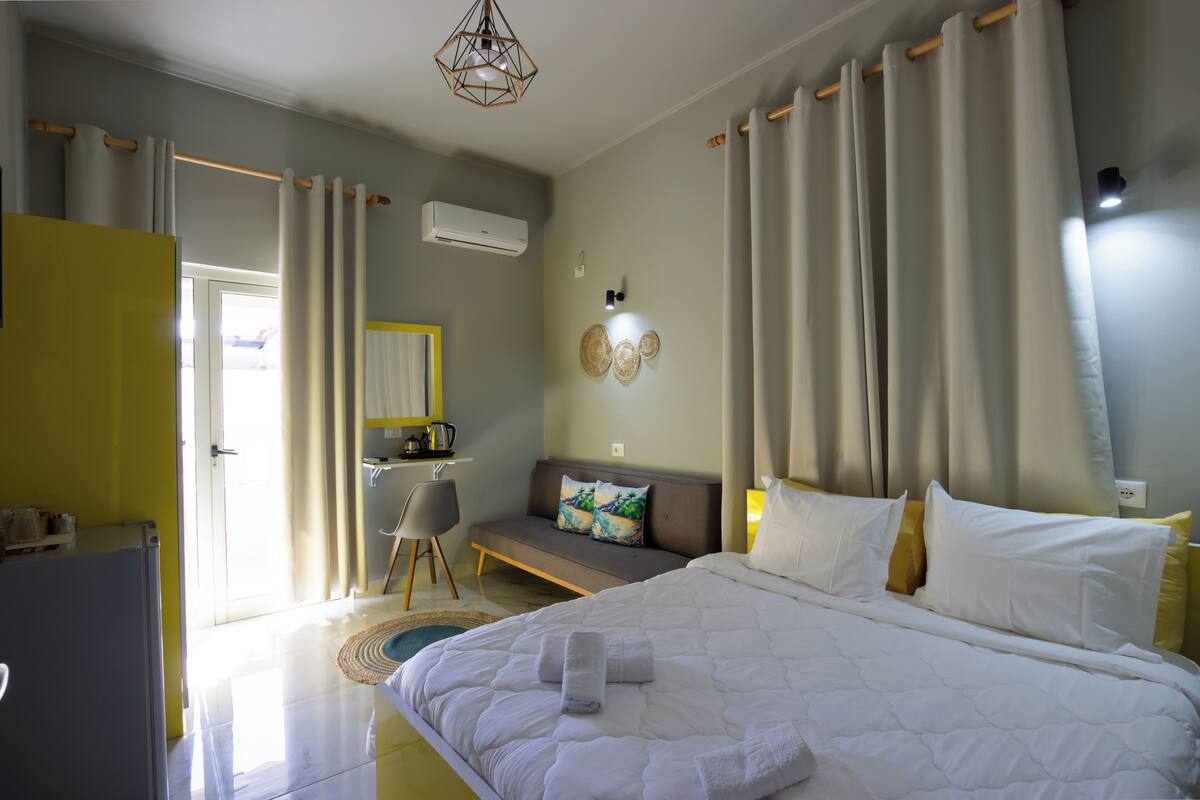 A bedroom with a bed, a desk, a chair, and a sofa.
