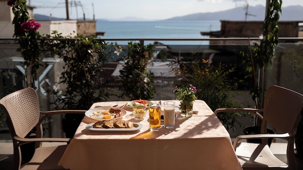 A table set for two with a view of the sea, a glass of beer, and a small vase with flowers. - Hotel Jonian (Sarandë)