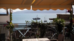 A terrace with a view of the sea, featuring a table and chairs, and a building with a balcony. - Hotel Jonian (Sarandë)