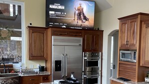 A modern kitchen with wooden cabinets, a stainless steel refrigerator, an oven, and a microwave.