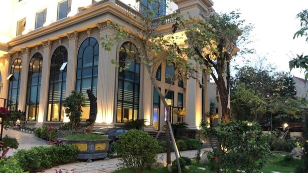 A building with large arched windows and a well-maintained garden with pathways and greenery. -  Quynh Trang Hung Yen Hotel (Nhu Quynh)