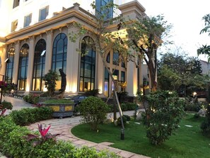 A building with large arched windows and a well-maintained garden with pathways and greenery. -  Quynh Trang Hung Yen Hotel (Nhu Quynh)