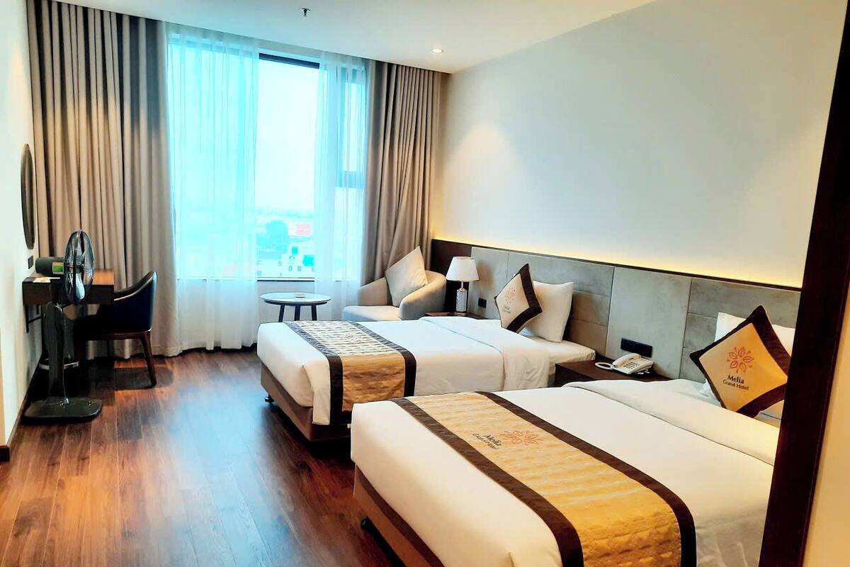 Une chambre d’hôtel avec deux lits, un bureau et une chaise.
