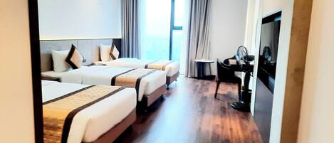 Habitación de hotel con dos camas, un escritorio y un ventanal grande.