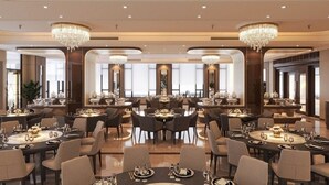 A spacious dining area with multiple tables and chairs, large chandeliers, and a view of the cityscape through large windows. -  Quynh Trang Hung Yen Hotel (Nhu Quynh)