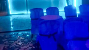A stage with a blue-lit backdrop and a person standing at the front. - Mike's Flat hotel (Kinshasa)
