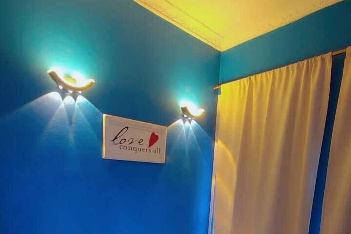 A room with a bed, a sign on the wall, and two wall-mounted lights.