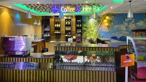A Coffee & Juice Bar with a tropical mural, wooden accents, and a sign pointing to the Prayer Hall.