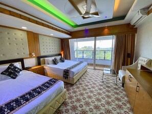A hotel room with two beds, a sofa, a desk, and a balcony with a city view. - CCULB Resort & Convention Hall (Ulukhola)
