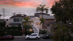 A residential area with houses, a street, and a view of the ocean at sunset.