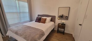 Une chambre à coucher avec un lit, une table de chevet avec une lampe et un tableau encadré au mur.
