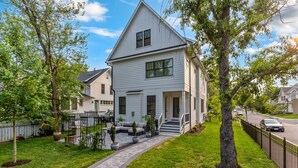 A two-story house with a front porch, a small garden, and a paved driveway. - The White House DC/Arlington (Arlington)