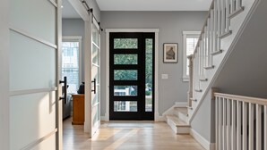 A hallway with a wooden floor, a black door, and a staircase with white railings. - The White House DC/Arlington (Arlington)