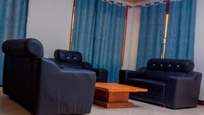 A room with two black sofas and a wooden coffee table. - Budget Double Room at Sabunyo Hotel Sironko (Sironko)
