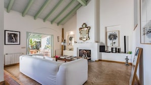 Ein geräumiges Wohnzimmer mit einem weißen Sofa, einem Kamin und einem großen Spiegel an der Wand.