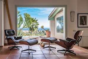 Un salon moderne avec deux canapés en cuir, une table basse et une vue sur une piscine et un espace verdoyant.