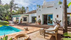 Ein modernes Haus mit Pool, Holzterrasse und Sitzgelegenheit im Freien.