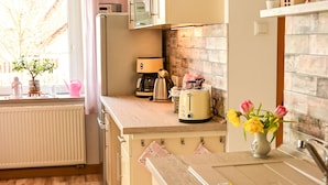 Una cocina con suelo de madera, un tostador, un lavamanos y una ventana con vistas a árboles.