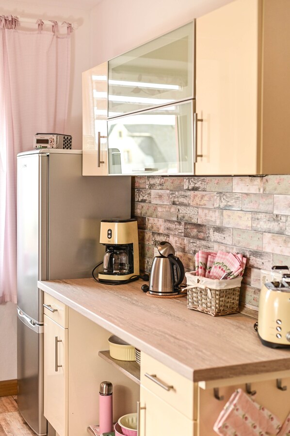 A compact kitchen with a refrigerator, coffee maker, toaster, and a microwave.