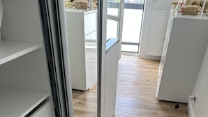 Eine moderne Küche mit weißen Schränken, Holzböden und Blick ins Freie.