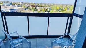Ein Balkon mit zwei klaren Plastikstühlen und einem Samsung-Kühlschrank.