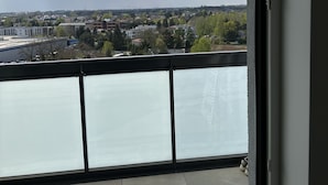 Ein Balkon mit Blick auf eine Stadtlandschaft, darunter Gebäude und eine Brücke.