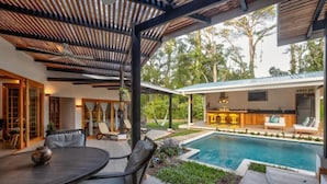 A covered outdoor area with a pool, seating, and a bar.