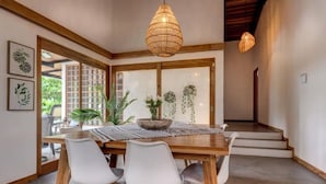 A dining area with a wooden table, white chairs, and a hanging light fixture.