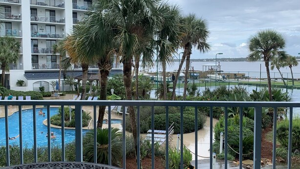 A pool area with a view of a building and a body of water. - Gorgeous 203C Gulf Shores Surf and Racket Club (Gulf Shores)