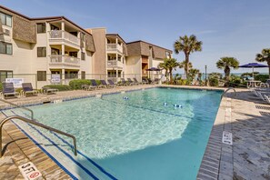 Relax by the pool surrounded by lounge chairs and umbrellas, with stunning views of the surrounding landscape.