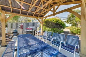 Relax in an outdoor seating area with a metal table and benches, barbecue grill, and trash can.
