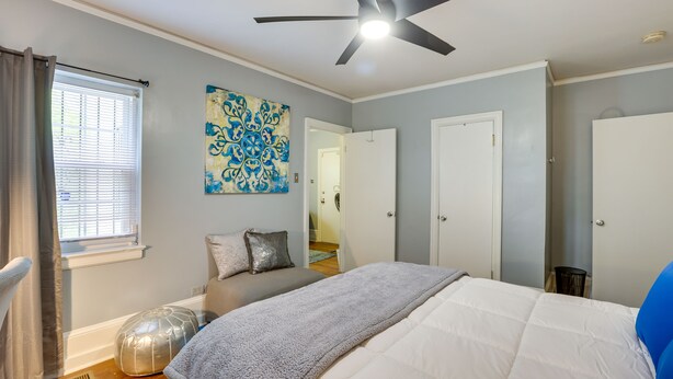A bedroom with a bed, a ceiling fan, a window with curtains, a door, and a wall decoration. - Cozy Tuskegee Home - 20 Mi to Auburn University! (Tuskegee)