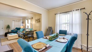 A dining area with a long table set for four, blue upholstered chairs, and a buffet table with a plant centerpiece. - Cozy Tuskegee Home - 20 Mi to Auburn University! (Tuskegee)