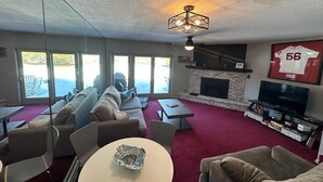 Una sala de estar con un sofá modular, una chimenea, un televisor y un ventanal con vistas.