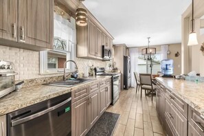 Una cocina moderna con encimeras de granito, electrodomésticos de acero inoxidable y armarios de madera.